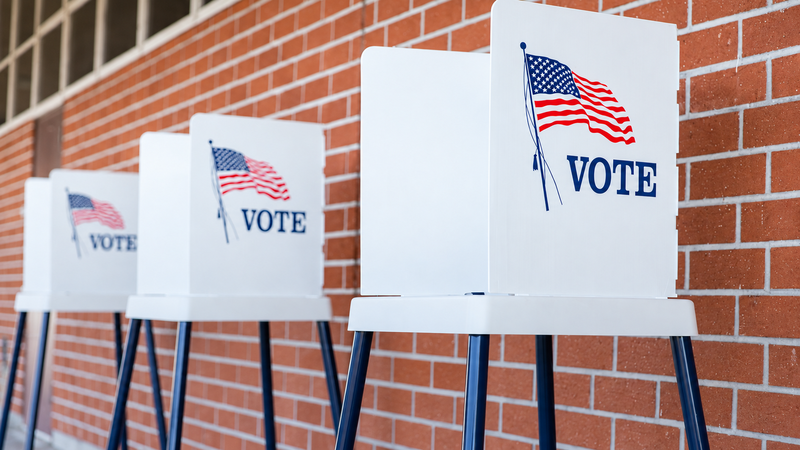 Voting booths with American flags outside a brick building